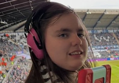 Kya wearing her noise-cancelling headphones, calm and settled